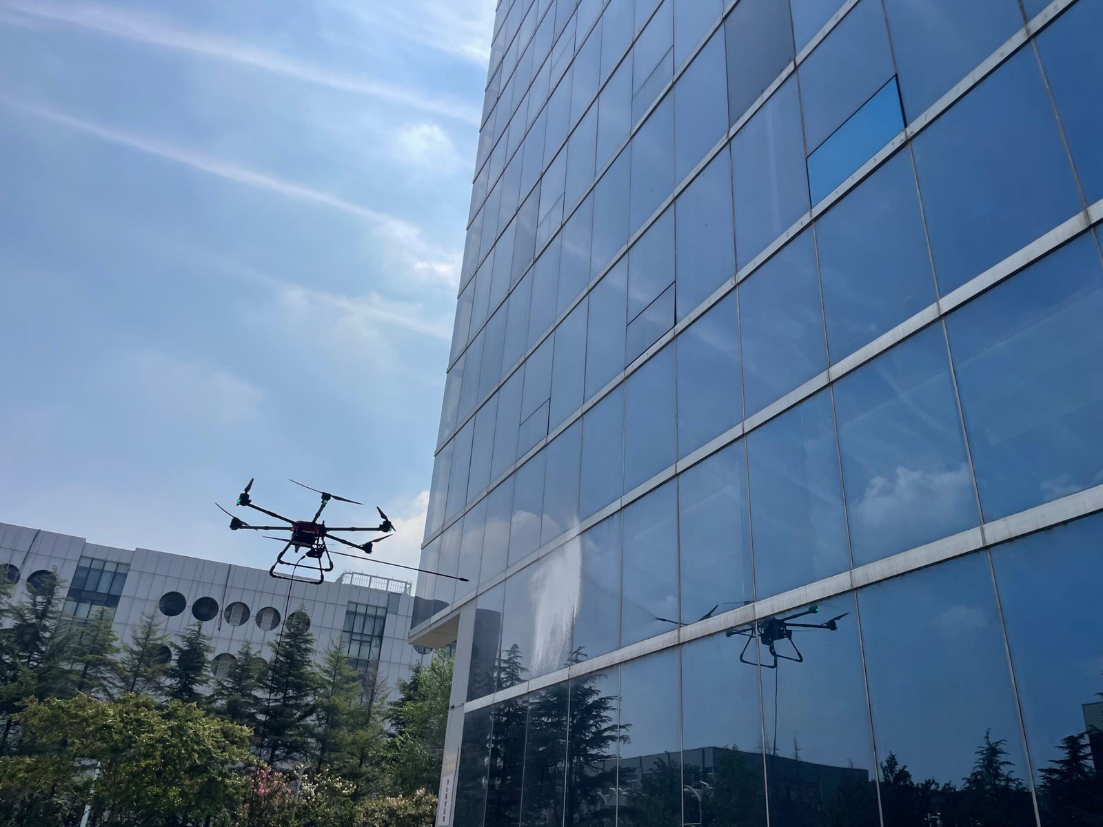 Professional commercial cleaning drone washing high-rise glass facade, industrial cleaning equipment for skyscrapers and solar panels
